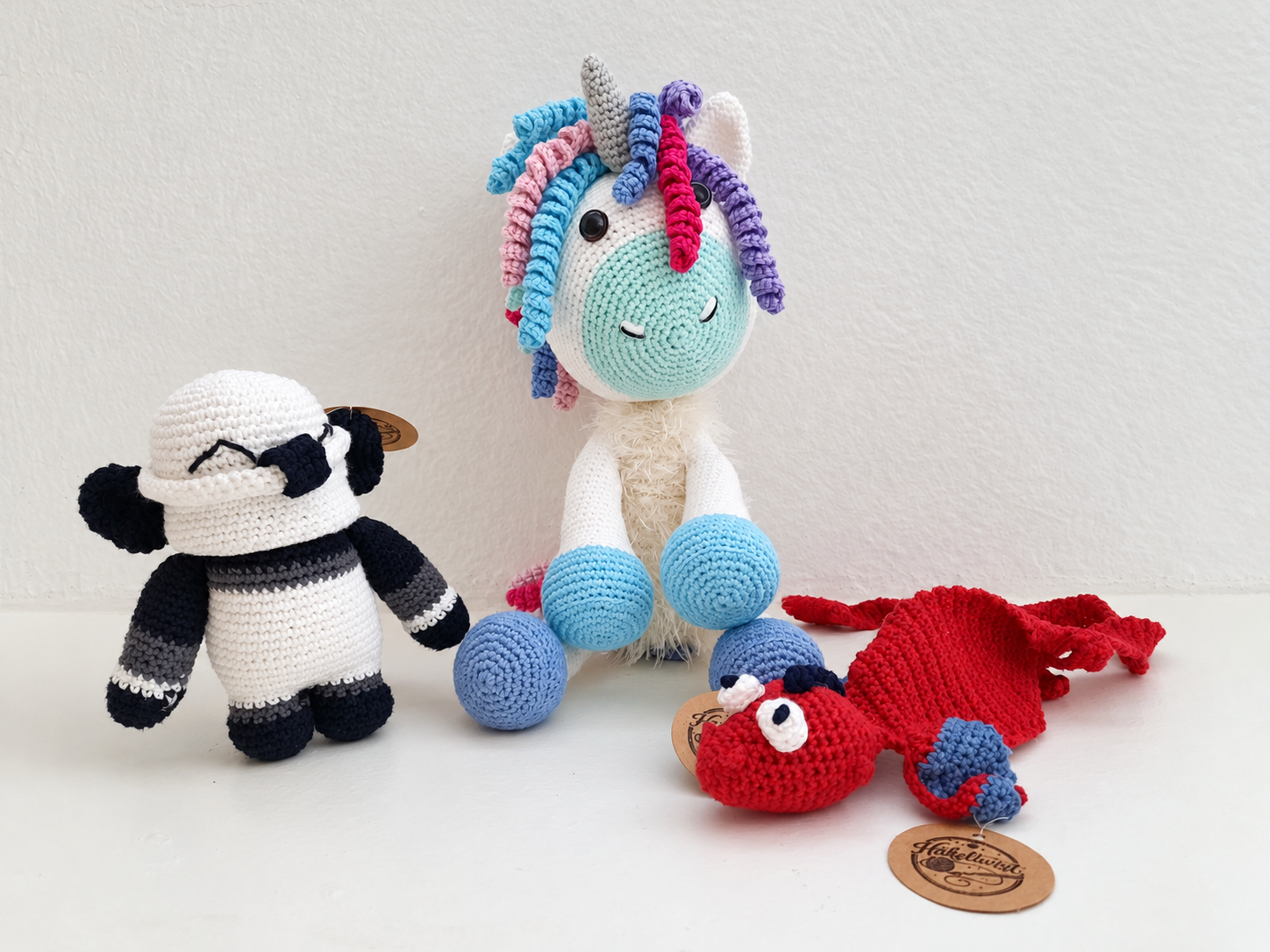 Gehäkeltes Einhorn, roter Drache und schwarz-weisse Figur